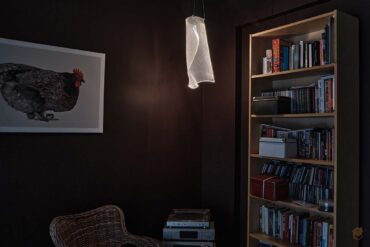 klimatyczny pokój z biblioteczką i wiszącą lampą pionową